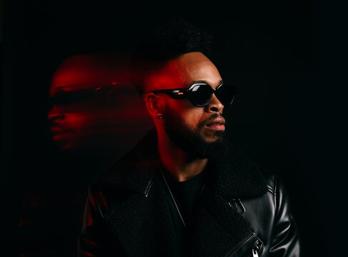 Stylish black man in sunglasses in dark room