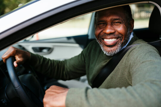 Happy mature man driving car