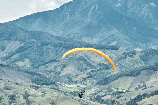 Person flying over a valley in paragliding