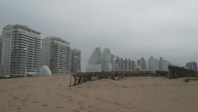 los dedos, public accessible sculpture of fingers reaching out of the sand in Punta del Este at the coastline of the atlantic ocean in Uruguay.