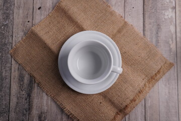 empty white glass cup and saucer on wooden table