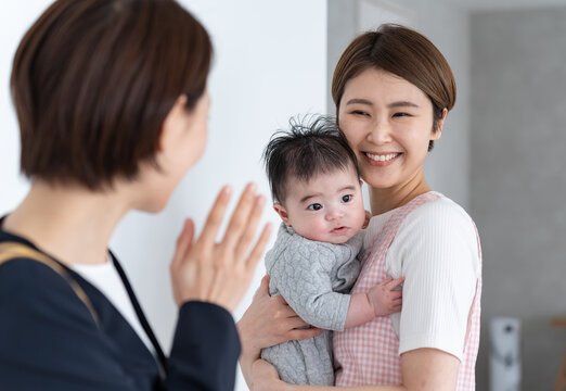 保育園に預けるお母さんと保育士