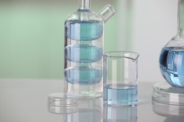 Laboratory analysis. Different glassware with liquid on white table against blurred background. Space for text