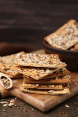 Cereal crackers with flax, sunflower and sesame seeds on wooden table, closeup