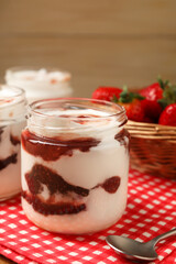 Tasty yoghurt with jam and strawberries on table, closeup
