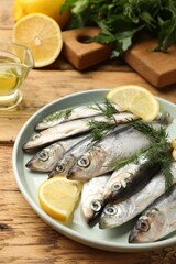 Fresh raw sprats, lemon and dill on wooden table, closeup