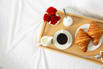 Tasty breakfast served in bed. Fresh croissants, coffee, honey and jam on wooden tray, space for text
