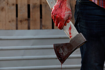 Man holding bloody axe outdoors, closeup. Space for text