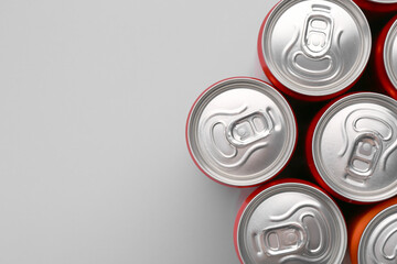 Energy drink in cans on grey background, top view. Space for text