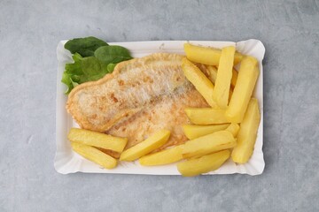 Delicious fish and chips with spinach and lettuce on gray table, top view