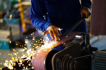 Blacksmith working with steel, polishing metal amidst sparks in bright  