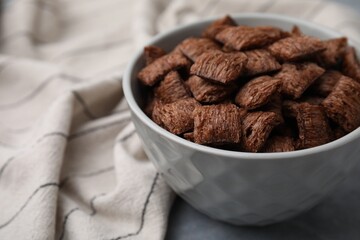 Chocolate cereal pads in bowl on grey table, closeup. Space for text