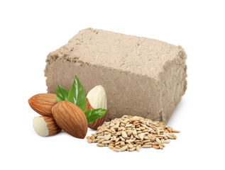 Tasty halva, peeled sunflower seeds, almonds and green leaves isolated on white
