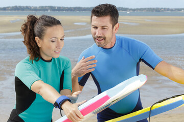 man showing partner how to position her bodyboard