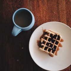 waffle breakfast with syrup and a blue cup of coffee