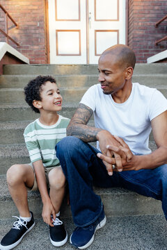 Man and child enjoying talking outside on steps.