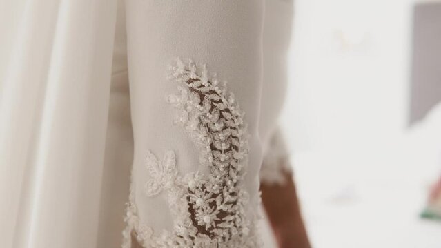 Close up wedding dress arm sleeve details, bride preparing for ceremony.