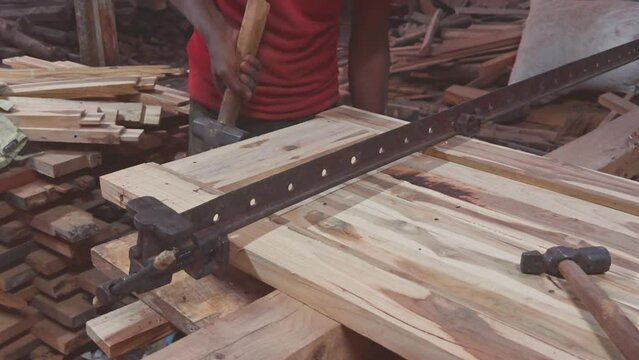 Closeup of a carpenter hands working on wooden planks with tools on a workbench in the workshop