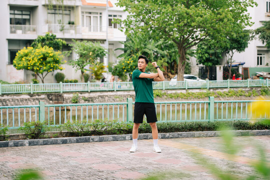 sporty asian young male in sportswear warming up his body