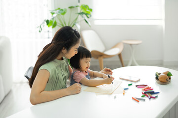 Asian young mother and cute daughter happy to do drawing