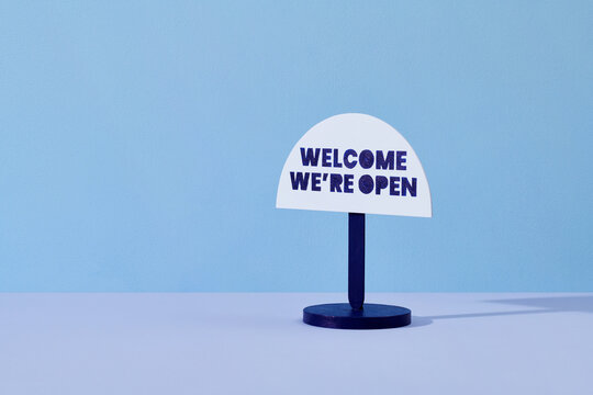 Welcome we are open signage hanging on pastel color background