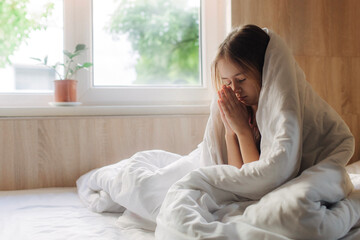 School age girl lies in bed with a respiratory illness at home. Close up photo copy space for text top above view. Pre-teen relaxing in bed bedroom. Health and Medicine concept