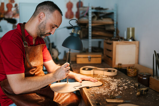 Focused woodworker creating ornament for violin