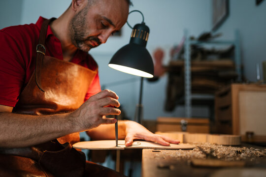 Professional woodworker carving violin body