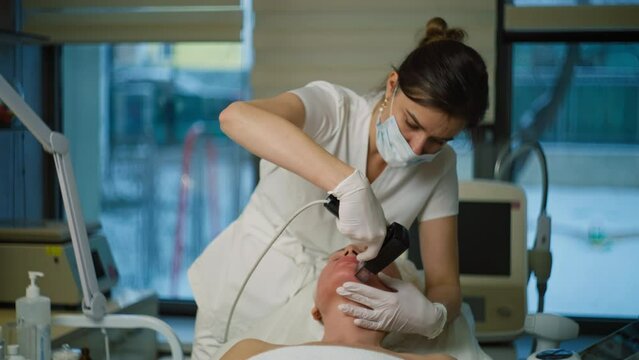 A cosmetologist performs rejuvenating procedures on an elderly woman. Beauty procedures using devices in the salon. High quality 4k footage