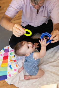 Candid photo of father playing with baby on the floor 