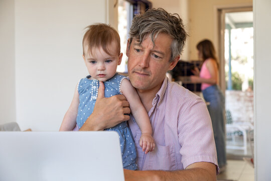 Father trying to get work done while holding his baby 