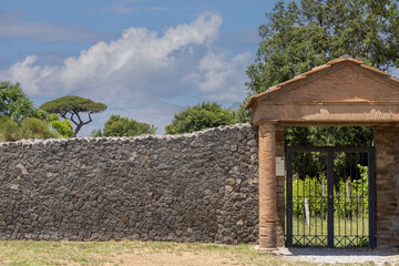 Garden entrance near Amphitheatre, peak of volcano Vesuvius in the distance, Pompeii, Naples, Italy