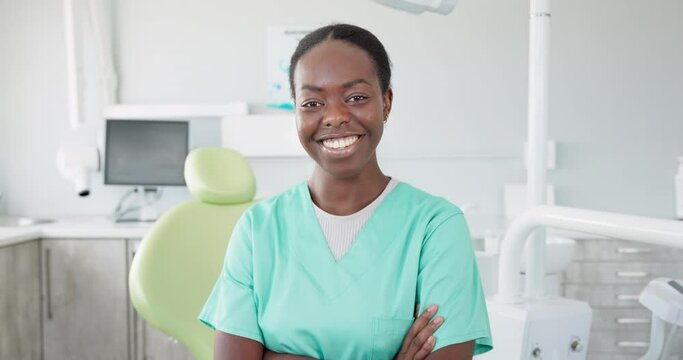 Face, dentist and arms crossed with black woman in scrubs at hospital for dental care or oral hygiene. Portrait, smile for healthcare and happy young orthodontist professional at clinic for dentistry