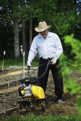 The farmer is digging a garden. A man with a harvester plows the garden. The gray-haired grandfather mows the garden.