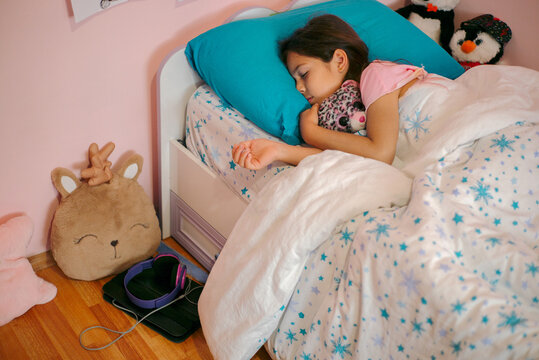 A little girl sleeps in a single bed  in her room