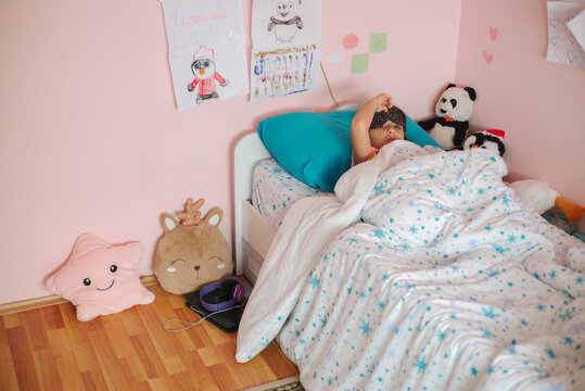 A little girl sleeps in a single bed  in her room