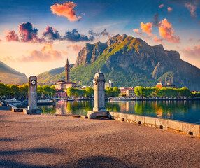 First sunlight glowing mountain peak and old buildings in Lecco town, city on the southeastern shore of Lake Como, Italy, Europe. Stunning sunrise in Italian Alps. Traveling concept background. - obrazy, fototapety, plakaty