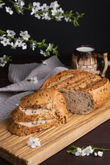 Pieces of fresh homemade rye bread with clay mug of milk on wooden cutting board. Healthy breakfast