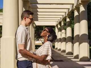 Happy multiracial couple embracing near pillars