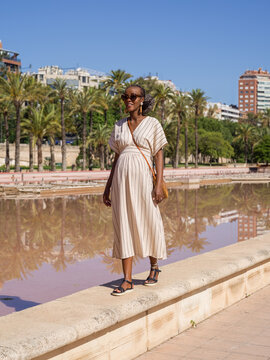 Black future mother walking on border near pond