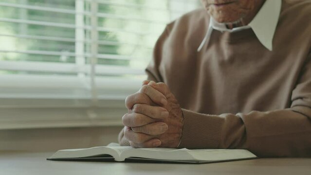 Grandfather sat with his hands clasped and prayed to the sacred scriptures on the window sill. Along with giving thanks to God Christian concept, Christian asking for blessings, scriptures and prayers