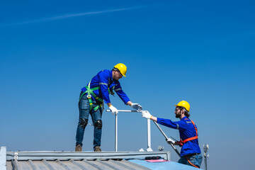 Roofer man helping hands to climbing on roof, work on height concept