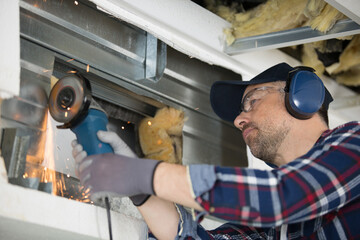 a man carpenter saws a window seal