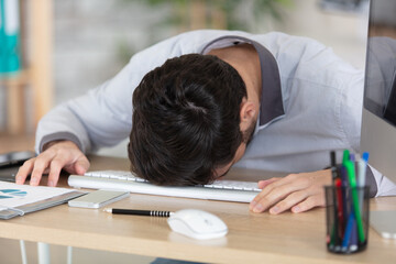 young man sleeping while sitting at his working place