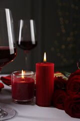 Place setting with roses and candles on white table, closeup. Romantic dinner