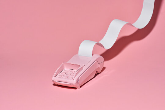 pos terminal with long cash register tape on pink background.