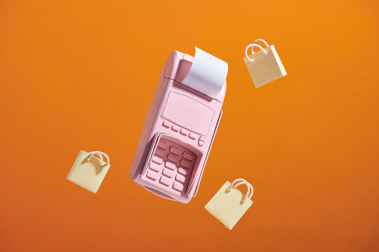 A compact cash register with  shopping bags floating around.