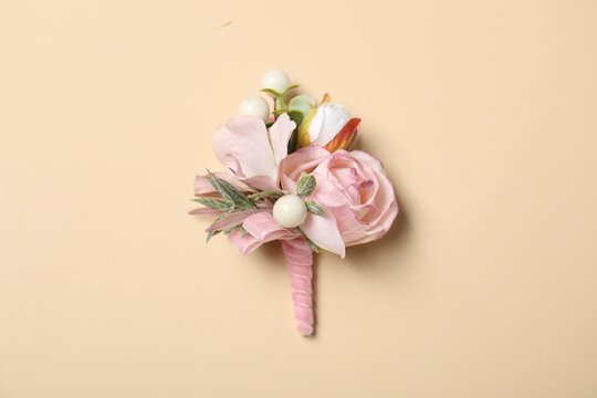 Stylish pink boutonniere on beige background, top view