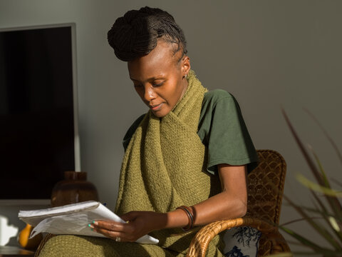 Focused woman studying in living room with sunlight