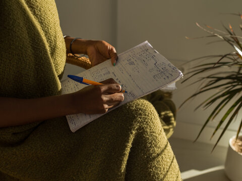 Crop woman writing Spanish words doing homework